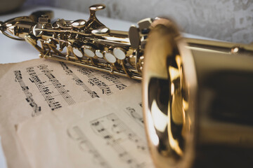 A close-up saxophone lies on the notes.