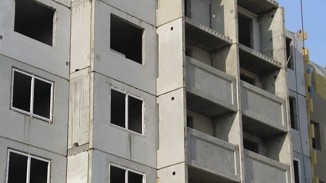 Installation of prefabricated building wall panels in construction works. Unfinished building of reinforced concrete panels without windows. Building structure made with prefabrication system
