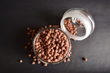 Top View of Closeup Brown Chickpea Beans in a Transparent Glass Jar On isolated Black Background