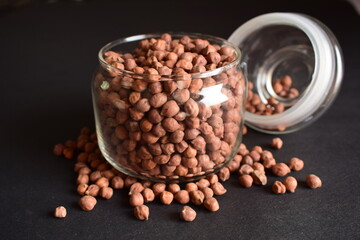 Closeup Brown Chickpea Beans in a Transparent Glass Jar On isolated Black Background
