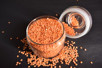 Top View Closeup Red Lentils in a Open Transparent Glass jar On isolated Black Background