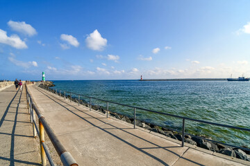 Obraz premium Two lighthouses, one green and one red are visible from the promenade boardwalk along the Baltic Sea coast at the town of Warnemunde, Germany.