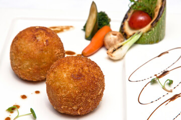 Chicken Kiev and roasted vegetables on a white plate, a white background. Breaded chicken breast stuffed with herbs and butter