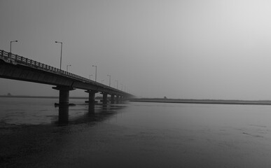 road bridge over river with its water reflection at dawn from low angle black and white
