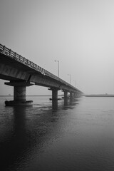 road bridge over river with its water reflection at dawn from low angle black and white