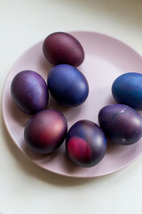 Painted blue and purple Easter eggs on a textured background. Easter eggs on a plate.