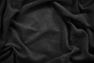 Beautiful black fabric background. Wavy soft folds. Elegant dark gray background with copy space for design.