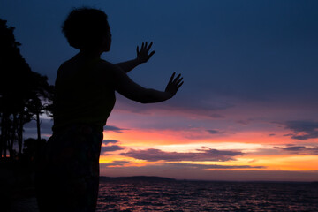 Fototapeta premium Beautiful woman silhouettes against the background of the sea and evening sunset.