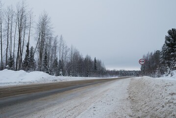 The road through the winter forest on a cloudy January morning. Western Siberia. Russia.