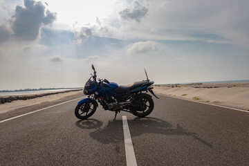 motorcycle isolated standing on tar road in sea shore background