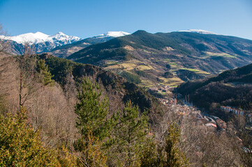 Fototapeta na wymiar Bosque alpino en el Pirineo con las montañas nevadas de Fondo. Ruta de senderismo por Ribes de Freser i Queralbs
