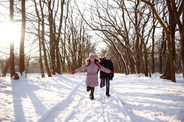 Fototapeta na wymiar Brother and sister run through the snowy forest. Winter activities for children. Frost, snow and rest.