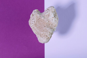 Levitation. Falling heart-shaped stone on a bright two-tone background. Stone heart close up. Valentine's day concept.