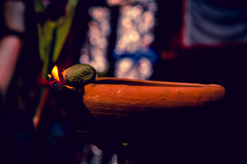 Creative Photography of A Realistic Burning Clay Oil Lamps in Diwali, An Indian Festival in Evening. Colorful Red, Yellow Orange Fire Flame Lit on Dark Night Shadow Background with Noise Grain Effect.