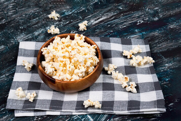 popcorn on dark background. Popcorn in a wooden bowl. Watching a movie with popcorn. Copy space.