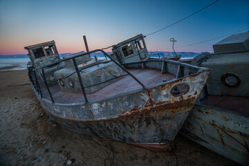 Fototapeta na wymiar rusty old ships standing in the ice of a frozen lake at sunset