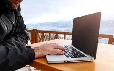 Side view of a male hands mountain climber using laptop on mountain peak