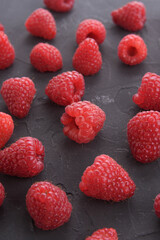 Pattern of raspberry on dark rock background. Flat lay summer berries - red raspberries. Creative minimalism. Frony view