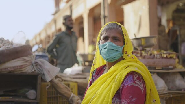 Close Shot Of Indian Local Market Where A Vegetable Vendor Woman Sitting With Protective Mask On Face Looking At Camera During The Hard Times Of Covid 19