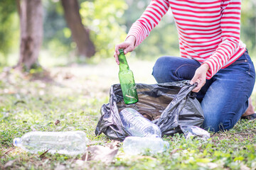 Woman hand picking up garbage plastic and Glass bottles for cleaning at park