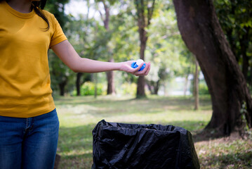 Woman hand picking up garbage plastic and Glass bottles for cleaning at park