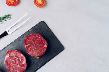 Raw veal medallions on black stone board
