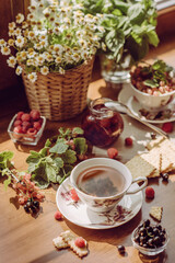 summer breakfast. a summer garden still life with a mug of tea, wildflowers and berries. garden aesthetics