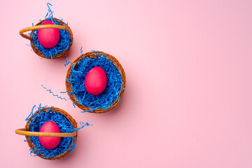 Painted Easter eggs in decorative nest on pink background