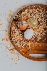 Three easter eggs on wooden background with sawdust around. Happy Easter card. Easter eggs with lace border, wooden cutting board on white table. Eggs decoration. Golden easter egg.