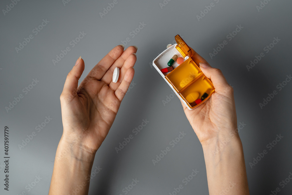 Wall mural A young woman holds a box for pills and a capsule in her hands. healthy lifestyle. Hands close up