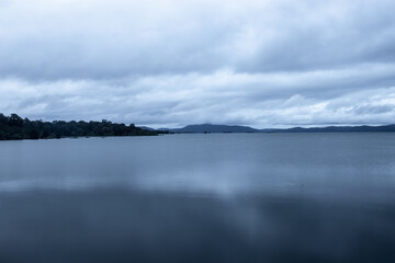 river serene back water with mountain shadow and dramatic cloudy sky long exposure image