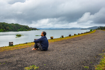 man young isolated watching the pristine nature at river edge with dramatic sky