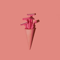 Ice cream cone with pink safety razors on a pastel pink background. Abstract creative beauty minimal concept. Trendy summer fashion idea.