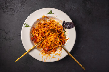 Pasta with cherry tomatoes, cheese and rosemary served on plate with spoon and fork on dark textured background, top view, copy space