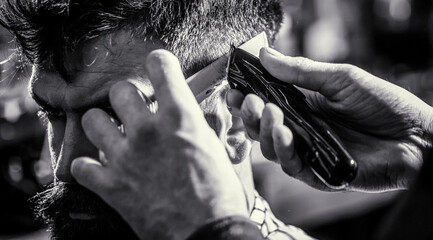 Hipster client getting haircut. Hands of barber with hair clipper, close up. Haircut concept. Man...