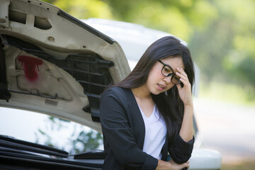 Asian business woman sad waiting for help by a broken car. Use a mobile phone to call the mechanic.