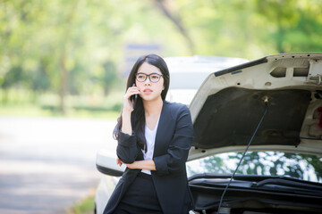 Asian business woman sad waiting for help by a broken car. Use a mobile phone to call the mechanic.