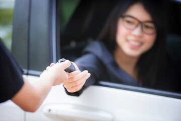 Asian woman sitting in a private car shows the keys in her hand.Selected focus