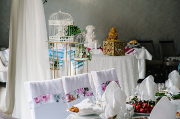 Festive table newlyweds covered with a tablecloth, decorated composition of flowers, greenery, cages in wedding banquet hall. Close up. Decor in style vintage.