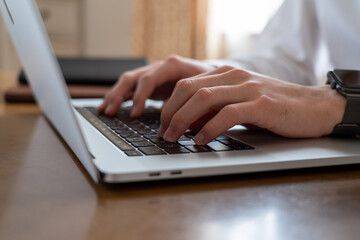 ノートパソコンのキーボードを打つ両手のクローズアップ
