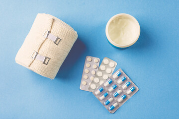 pills and medical elastic bandage on blue background.