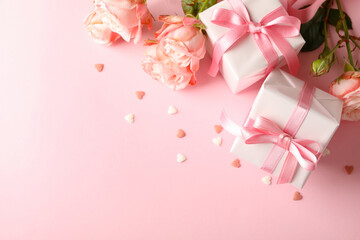 Roses and gift boxes on pink background, space for text