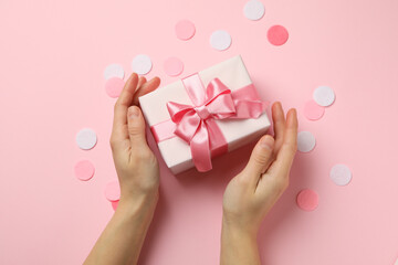 Female hands holding gift box on pink background