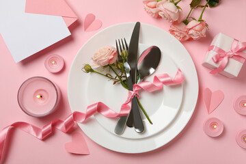 Concept of Valentine's day with cutlery, roses and ribbon on pink background