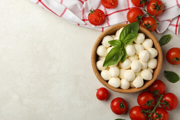 Fototapeta na wymiar Bowl with mozzarella and basil, tomato and towel on white textured background, space for text