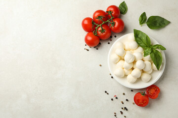 Plate with mozzarella and basil, tomato and pepper on white textured background, space for text