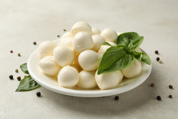 Plate with mozzarella and basil and pepper on white textured background, close up