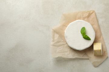 Baking paper with camembert cheese on white textured background