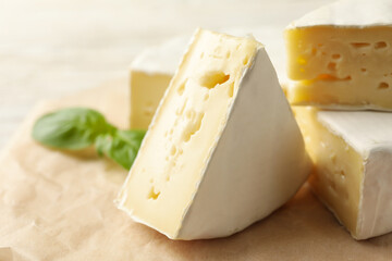 Baking paper with camembert cheese and basil, close up