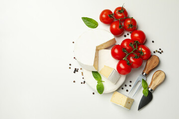 Naklejka na ściany i meble Camembert cheese, basil, tomato, knives and pepper on white background, space for text